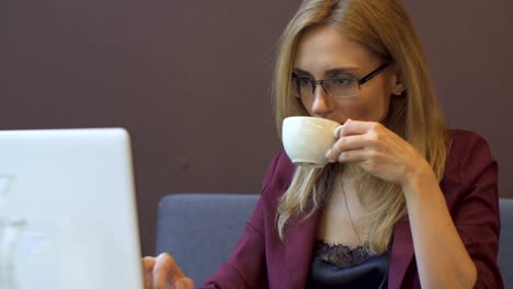 Young-attractive-businesswoman-working-on-modern-laptop-in-cafe