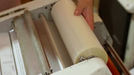 Hands-of-white-man-run-a-roll-laminator-during-its-work.-Closeup-view