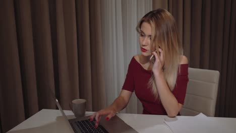 Cute-beautiful-young-business-woman-calling-by-phone-and-working-on-laptop-in-restaurant-with-a-cup-of-coffee