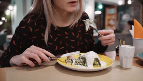 Unrecognizable-girl-eating-dessert-strudel-at-the-restaurant-using-fork-and-knife