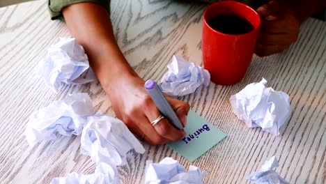 Female-executive-writing-on-sticky-notes-while-having-coffee-4k