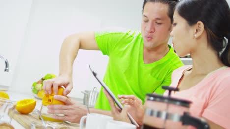 Ethnic-Couple-Kitchen-Counter-squeezing-Breakfast-Orange-Juice