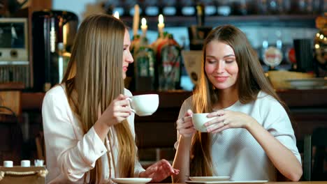 Two-young-female-friends-meeting-in-cafe