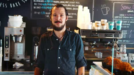 Porträt-von-männlichen-Barista-hinter-Theke-In-Coffee-Shop