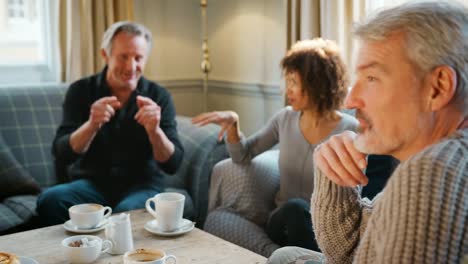 Gruppe-der-mittleren-Alter-Freunde-treffen-um-Tisch-im-Café