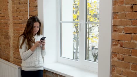 Beautiful-woman-drinking-coffee-using-smartphone-at-the-loft-modern-office