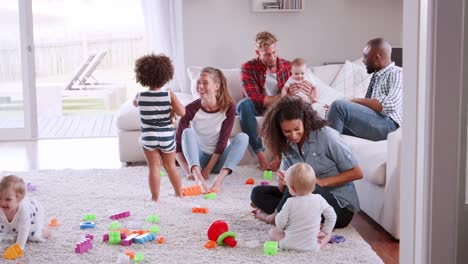 Amigos-con-niños-pequeños-jugando-y-sostener-taza-de-cofffee