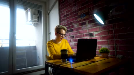 Attraktive-junge-Frau-an-der-Rezeption-mit-einem-Laptop-im-home-Office.