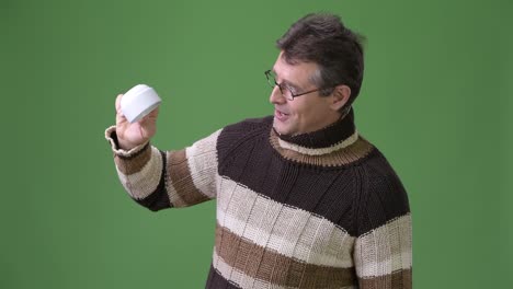 Mature-handsome-man-wearing-turtleneck-sweater-against-green-background