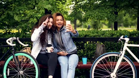 Best-friends-are-taking-selfie-with-smartphone-posing-for-funny-pictures-making-moustache-from-hair-then-hugging-and-taking-photos.-Modern-lifestyle-concept.