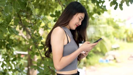 Asiatische-Frauen-Telefon-spielen-und-trinken-heißen-Kaffee-in-Coffee-Shop.