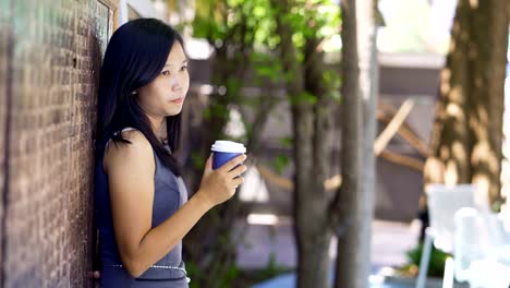 Asian-women-drink-hot-coffee-in-a-coffee-shop-happily.