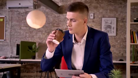 Young-serious-businessman-is-watching-in-tablet,-drink-coffee,-communication-concept,-business-concept