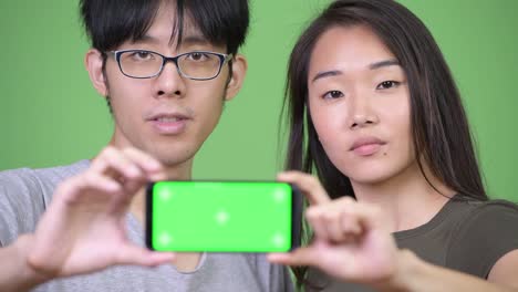 Junge-asiatische-Paar-zeigt-Handy-zusammen