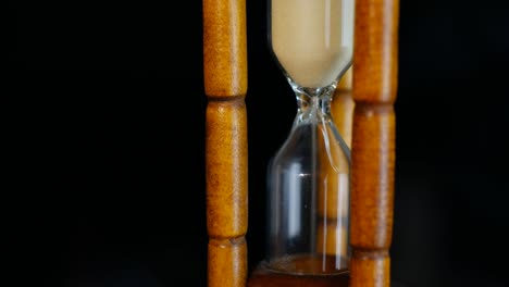 Close-up-View-Sand-in-Sanduhr-oder-Sanduhr-Zeit-Countdown.-auf-schwarzem-Hintergrund-isoliert