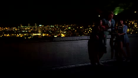 Friends-playing-guitar-on-a-rooftop-with-skyline-in-the-background