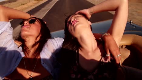 Boho-girls-enjoying-backseat-of-convertible-car-with-closed-eyes