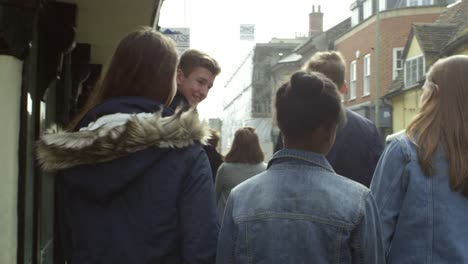 Rear-View-Of-Teenagers-Walking-Along-Street-Shot-On-R3D