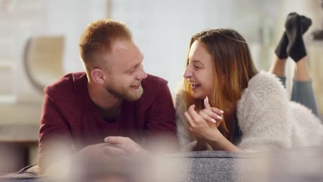 Young-natural-couple-in-love-lying-on-sofa-and-laughing