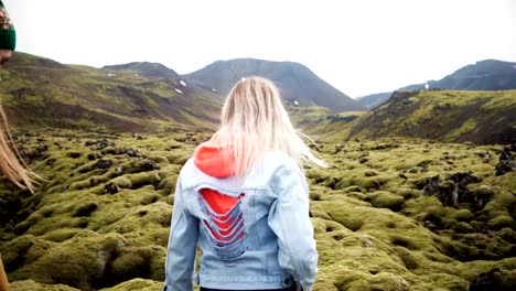 Rückseite-des-zwei-Touristen-Frau-gemeinsam-Wandern-in-Island.-Mädchen-zu-Fuß-durch-das-Lavafeld-bedeckt-Moos