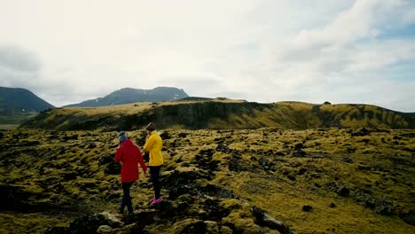 Aerial-view-of-the-tourists-walking-on-the-lava-field-in-Iceland.-Two-woman-hiking-on-the-mountain,-enjoying-the-hobby