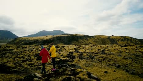 Vista-aérea-de-turistas-caminando-por-el-campo-de-lava-en-Islandia.-Mujer-dos-caminatas-en-la-montaña,-disfrutando-de-la-afición