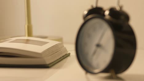 close-up-of-an-alarm-clock-beside-a-book