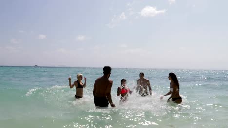 Gente-chapoteando-en-el-agua-que-se-divierten-en-la-playa,-mujeres-y-hombres-alegres-grupo-de-turistas-de-vacaciones