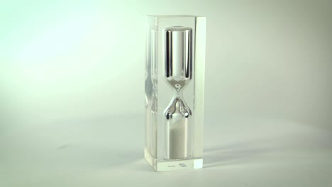 Modern-glass-hourglasses-rotate-against-a-white-background