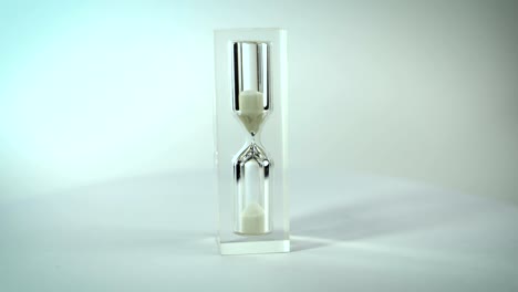 Modern-glass-hourglasses-rotate-against-a-white-background