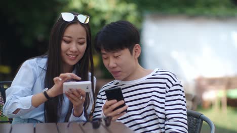 Asiatische-Teens-mit-Gadgets-im-Café-im-freien