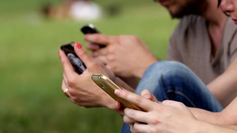 hands-of-young-students-at-the-park-typing-on-the-smartphones