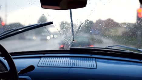 Punto-de-vista-desde-el-asiento-delantero-para-parabrisas-de-coche-retro-viejo-durante-mal-tiempo.-Limpiadores-de-quitar-las-gotas-de-lluvia-desde-la-ventana-del-automóvil-vintage-durante-el-paseo-en-la-carretera.-Cerrar-lenta