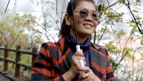 Asiatin-mit-Regen-Regenschirm-Wandern-in-Jigoku-Noboribetsu-eine-der-beliebtesten-reisen-reiseziel-Hokkaido-japan