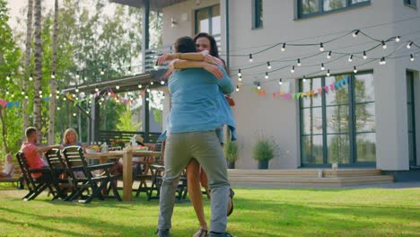 Beautiful-Young-Girl-Runs-Toward-Her-Boyfriend,-He-Catches-Her-and-They-Hug,-Spin-and-Dance-Together.-Two-Young-People-Embrace-in-the-Backyard-of-a-Garden-on-a-Hot-Summer-Day.-In-Slow-Motion.