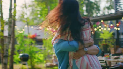 Beautiful-Young-Girl-Runs-Toward-Her-Boyfriend,-He-Catches-Her-and-They-Hug,-Spin-and-Dance-Together.-Two-Young-People-Embrace-in-the-Backyard-of-a-Garden-on-a-Hot-Summer-Day.-In-Slow-Motion.