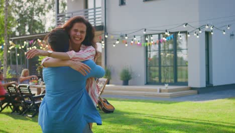 Beautiful-Young-Girl-Runs-Toward-Her-Boyfriend,-He-Catches-Her-and-They-Hug,-Spin-and-Dance-Together.-Two-Young-People-Embrace-in-the-Backyard-of-a-Garden-on-a-Hot-Summer-Day.-In-Slow-Motion.