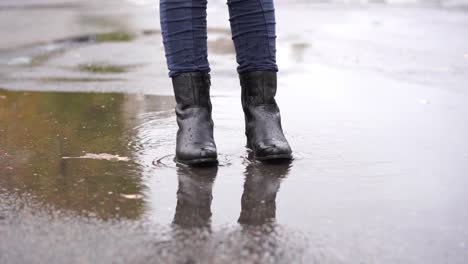 a-girl-in-black-leather-boots-stumbles-in-the-autumn-puddle-during-the-rain