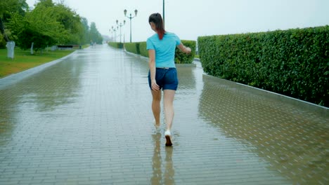 Mujer-feliz-saltando-bajo-la-lluvia-por-el-callejón