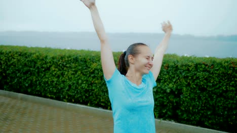 Mujer-feliz-girando-con-las-manos-hacia-arriba-y-los-ojos-cerraron-en-la-lluvia-torrencial