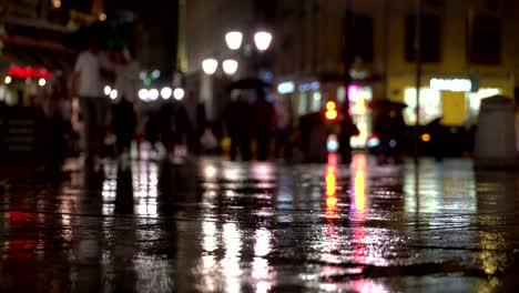 Zusammenfassung-Hintergrund-regnerischen-späten-Abend-in-der-Stadt-in-dunklen-Tönen-Naturale.-Regentropfen-fallen-auf-dem-bunten-Asphalt-von-Straßenlaternen-beleuchtet.-Unter-der-Menge-von-Fußgängern-gehen-Sie-zwei-Freunde-unter-Sonnenschirmen-und-sprechen.-Lebensstil-der-modernen-Stadt