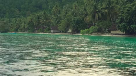 Lluvia-tropical-sobre-las-chozas-de-homestay-de-bambú-en-la-playa,-isla-de-Gam,-Raja-Ampat,-Papúa-Occidental,-Indonesia