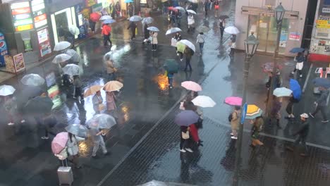 Menge-von-Menschen-zu-Fuß-mit-Sonnenschirmen-bei-Regen-auf-Dotonbori-Street,-Osaka,-Japan