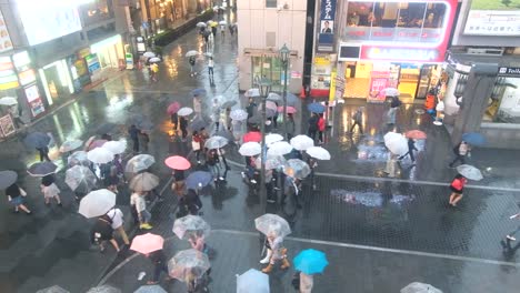 Menge-von-Menschen-zu-Fuß-mit-Sonnenschirmen-bei-Regen-auf-Dotonbori-Street,-Osaka,-Japan