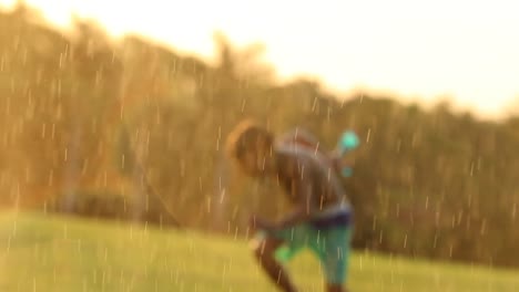 Escena-de-sueño-Cándido-de-niño-jugando-con-salpicaduras-de-agua-durante-el-atardecer.-Joven-saltando-y-tener-la-diversión-con-las-cosas-simples-en-vida,-un-agua-rociar-en-el-césped-en-4k-resolución-de-Clip