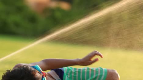 Child-having-fun-with-water-sprinkle-in-the-outdoor-lawn.-Young-boy-enjoying-the-simple-things-in-life-in-dreamy-60fps-4k-resolution-of-child-jumping-and-having-fun