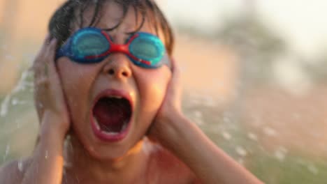 Child-screaming-covering-ears-with-hands.-4k-resolution-of-child-yelling-from-the-top-of-his-lungs-while-water-sprinkles-spray-him-with-water-in-60fps-slow-motion