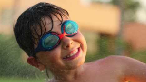 Niño-feliz-sonriendo-a-la-cámara-mientras-se-rocía-con-chispitas-de-agua-en-resolución-4k-de-60fps.-Infantil-buscando-positivo-sonriendo-a-la-cámara-durante-el-atardecer-de-verano-vacaciones-vacaciones-4k.mov