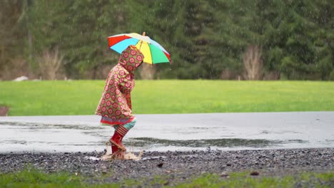 Junges-Mädchen-mit-Regenschirm-spielen-im-Regen,-Slow-motion