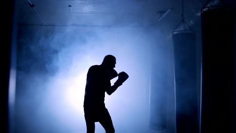 Silhouettes-of-a-boxer-trains-in-dark-gym